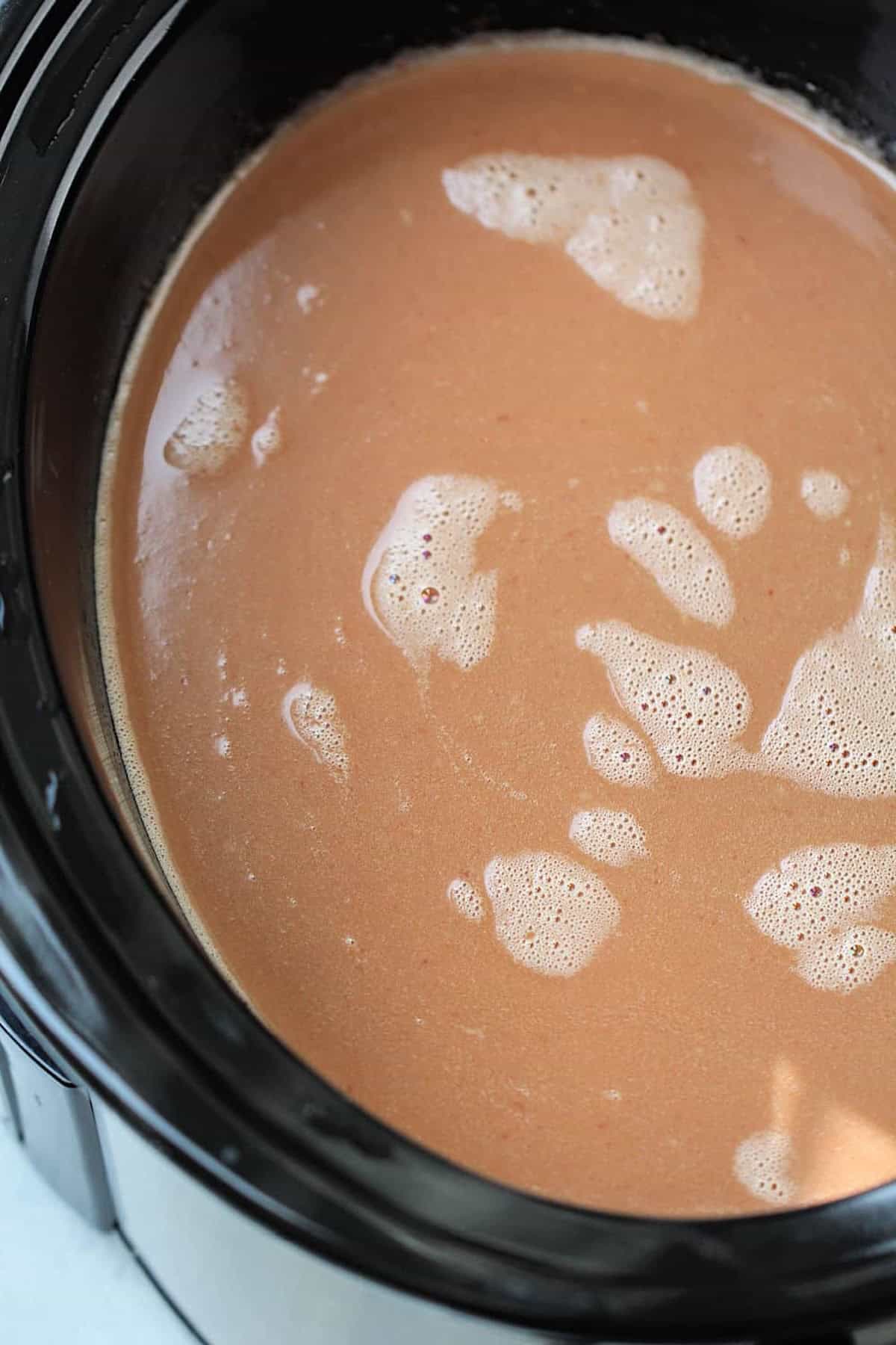 Close-up of a slow cooker filled with frothy hot chocolate.