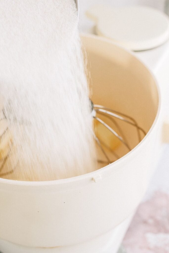 Adding dry ingredients to stand mixer with sugar cookie dough mixture.