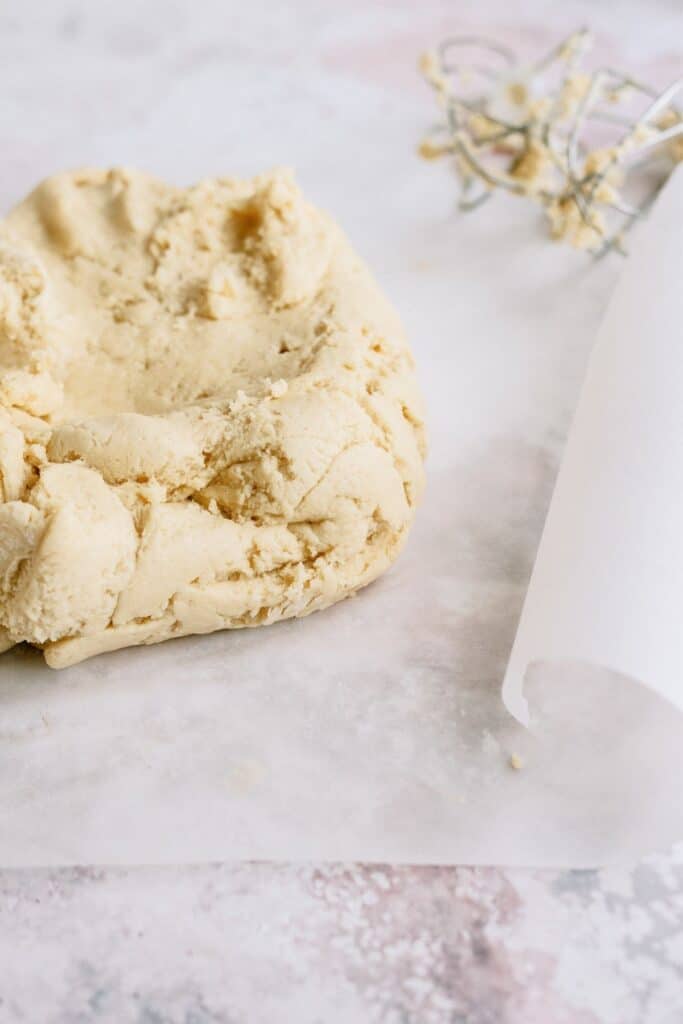 Sugar cookie dough on top of parchment paper on a counter.