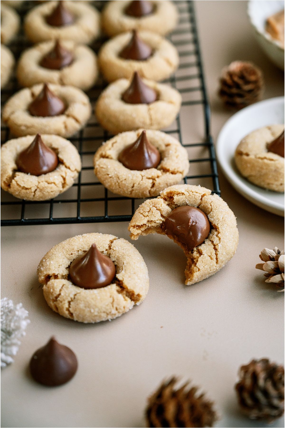 Peanut Butter Blossoms (Hershey’s Kiss Cookies) on a cooling rack with 2 cookies in the front, one has a bite taken out of it.