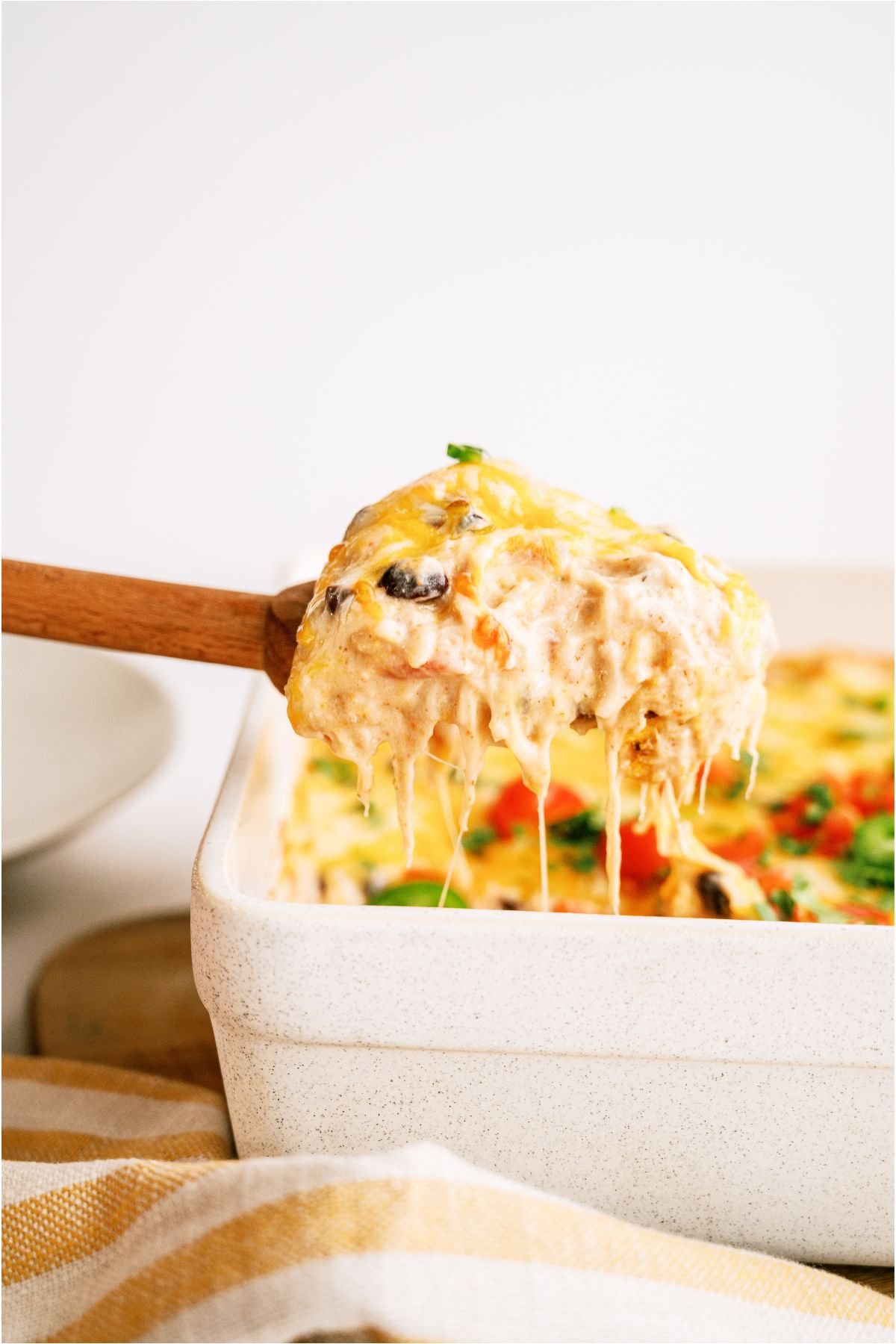 A wooden spoon lifting out a serving of Chicken Taco Casserole.