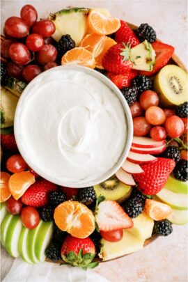 A platter of sliced fruit with a small bowl of Easy Cream Cheese Fruit Dip in the center of the platter.