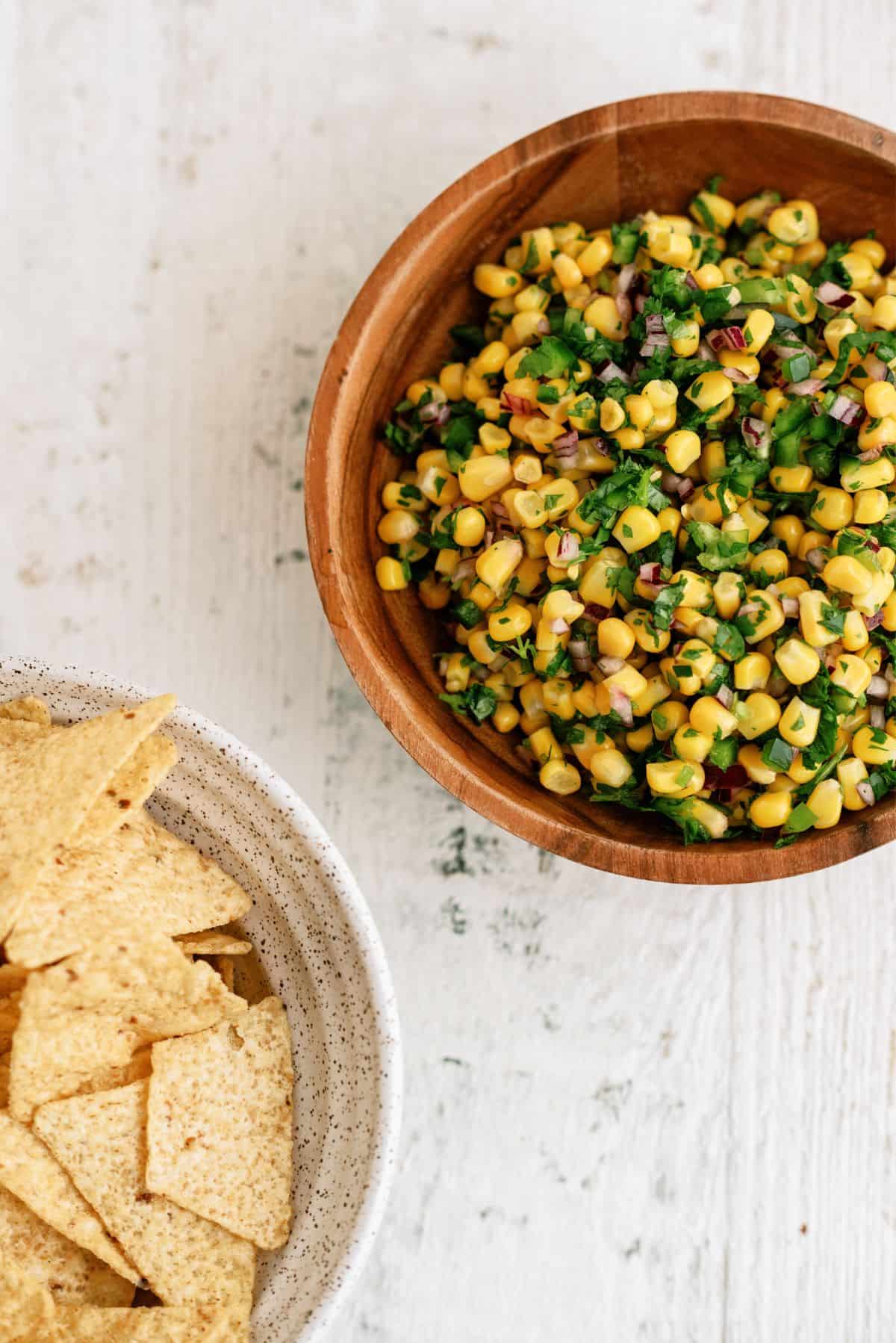 A bowl of Copycat Chipotle Corn Salsa Recipe and a bowl of chips