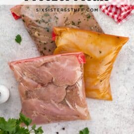 Three bags of prepared freezer meals lie on a countertop next to parsley, peppercorns, and a red-checkered cloth.