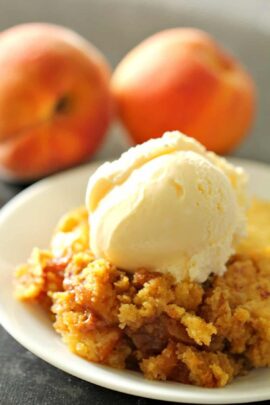 A slice of Slow Cooker Peach Cobbler topped with ice cream