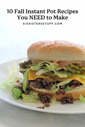 A hamburger with lettuce, cheese, and ground beef on a sesame bun placed on a white plate.
