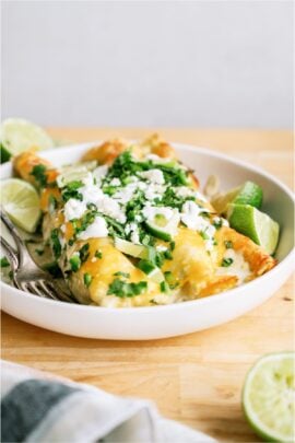 Two Honey Lime Chicken Enchiladas on a plate, topped with cheese and cilantro.