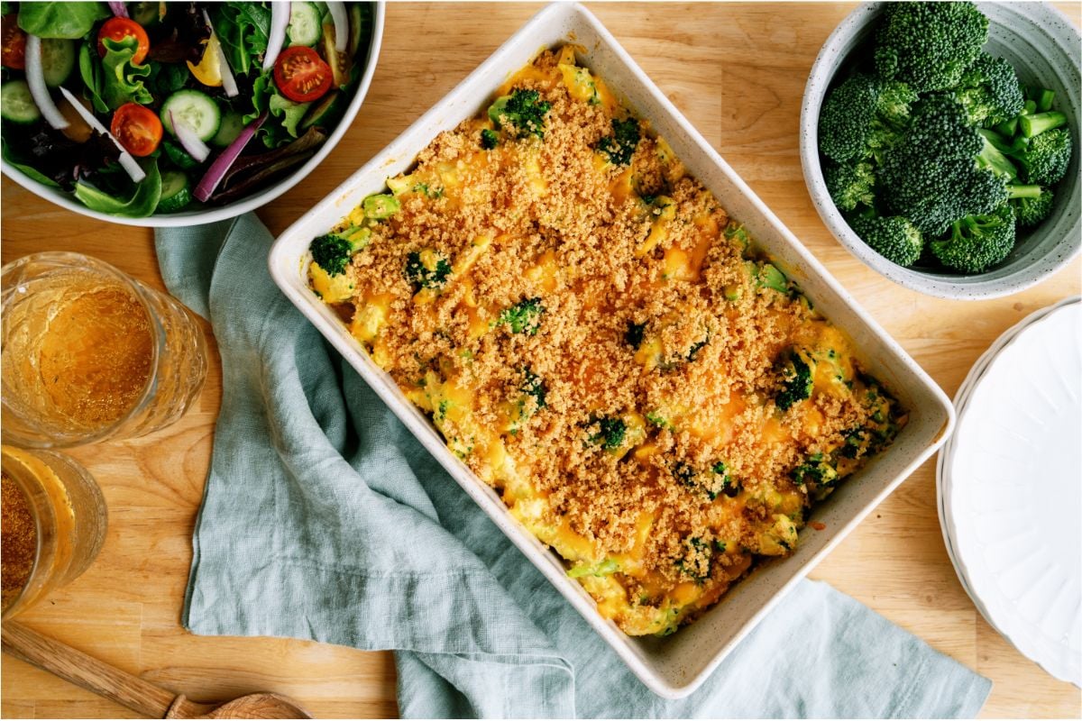 Top view of Chicken and Broccoli Casserole in casserole dish with a salad in the background and a bowl of fresh broccoli. 