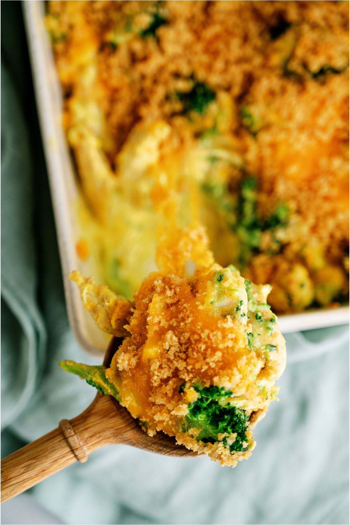 A wooden spoon scooping a serving of Chicken and Broccoli Casserole out of the casserole dish.