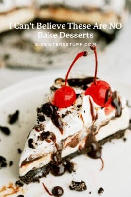 A slice of dessert with a chocolate cookie crust, creamy topping, two red cherries, chocolate drizzle, and cookie crumbs, on a white plate.