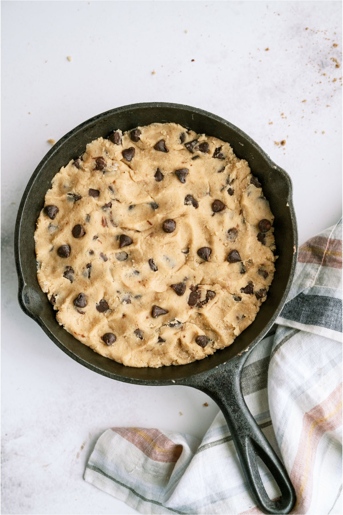 Chocolate chip cookie dough pressed into a skillet.