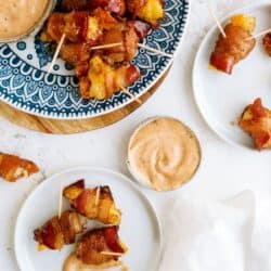 Plates of bacon-wrapped tater tots on skewers, served with dipping sauce in small bowls.