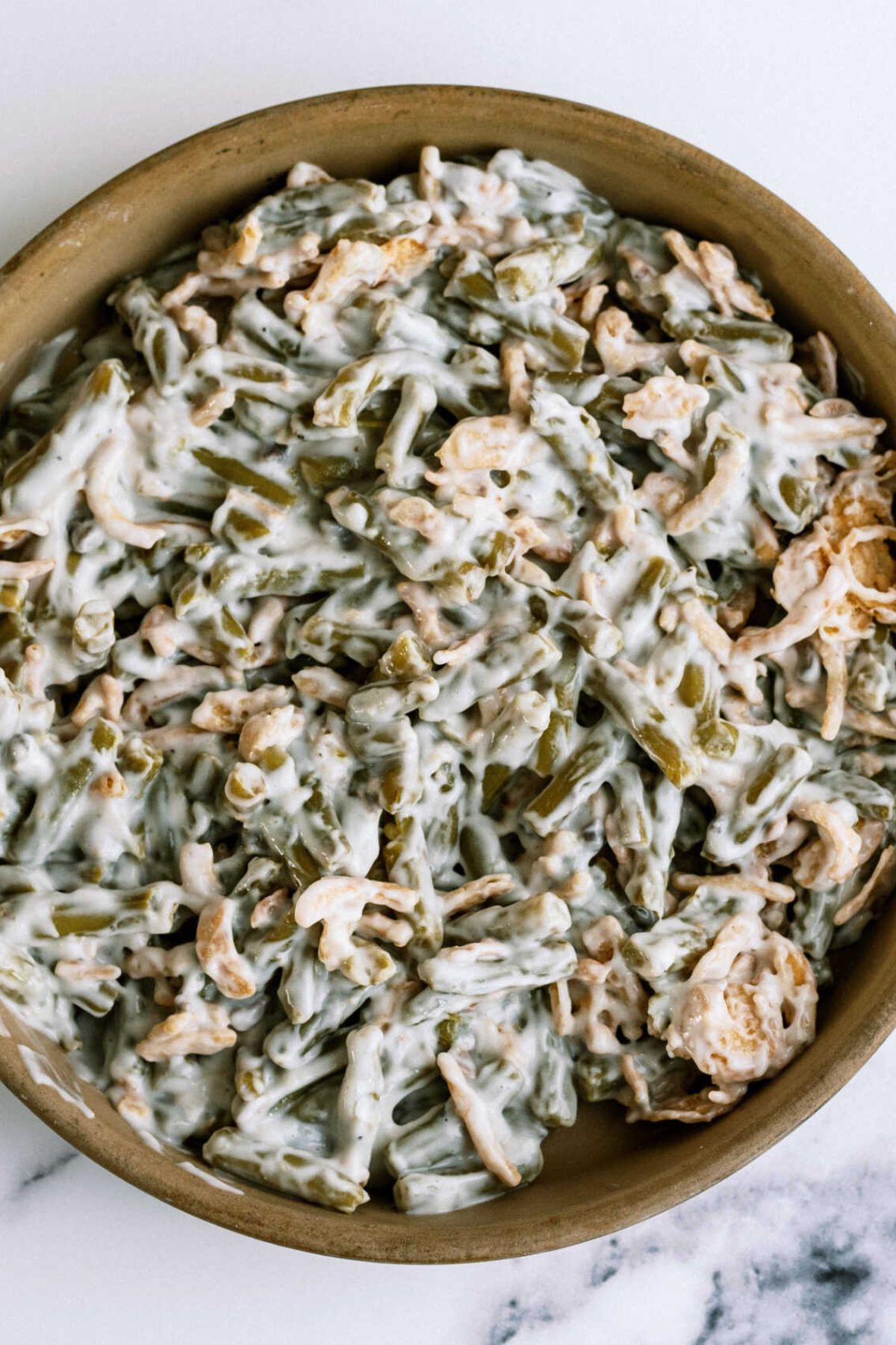 Close up of unbaked Classic Green Bean Casserole in a casserole dish.