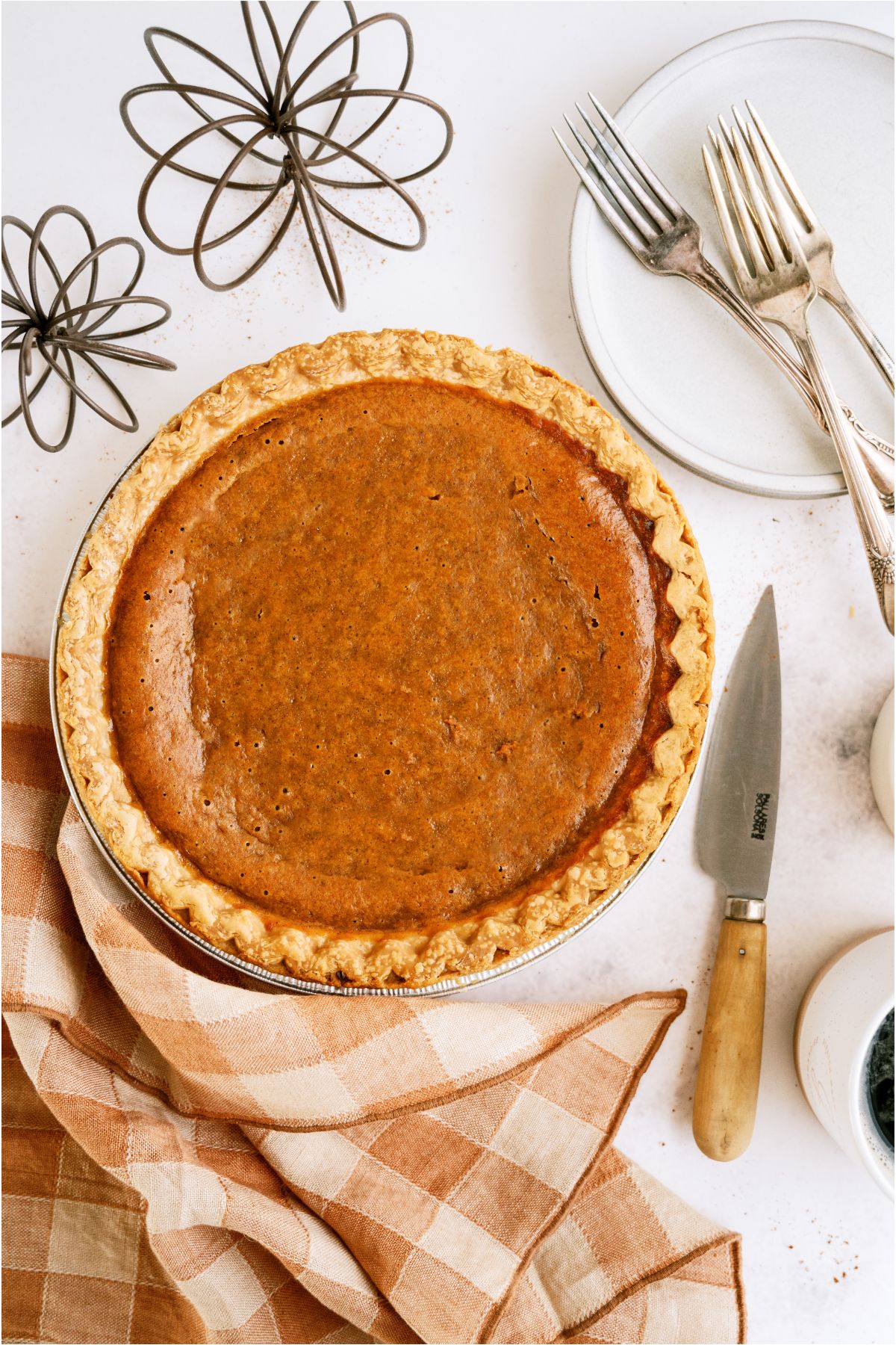 Top view of an Easy Pumpkin Pie on a table with decor and a checkered towel.