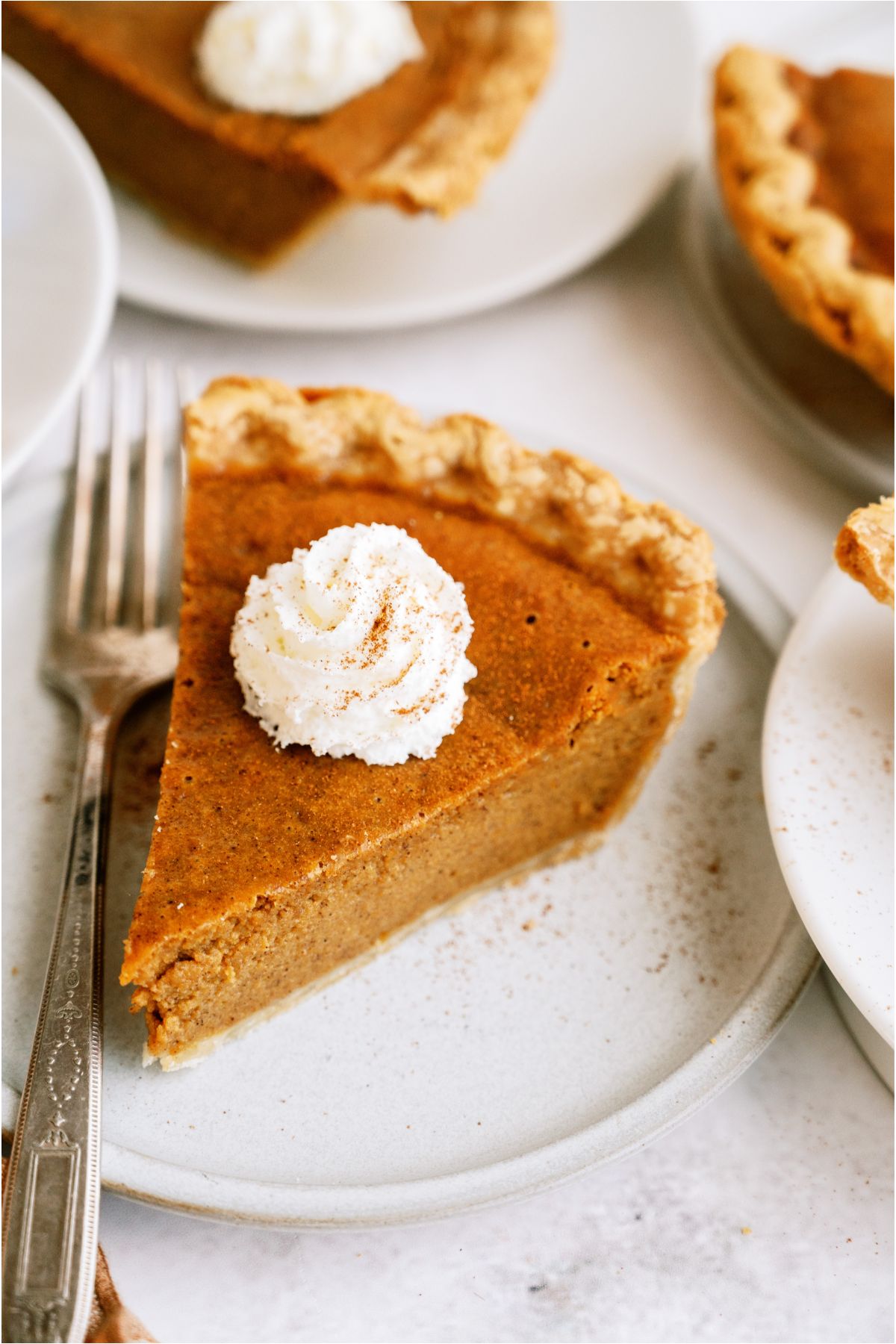 A slice of Easy Pumpkin Pie topped with whip cream on a plate with a fork.