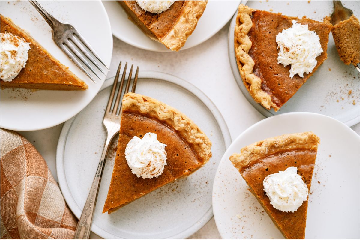 Several slices of A slice of Easy Pumpkin Pie topped with whip cream on plates.