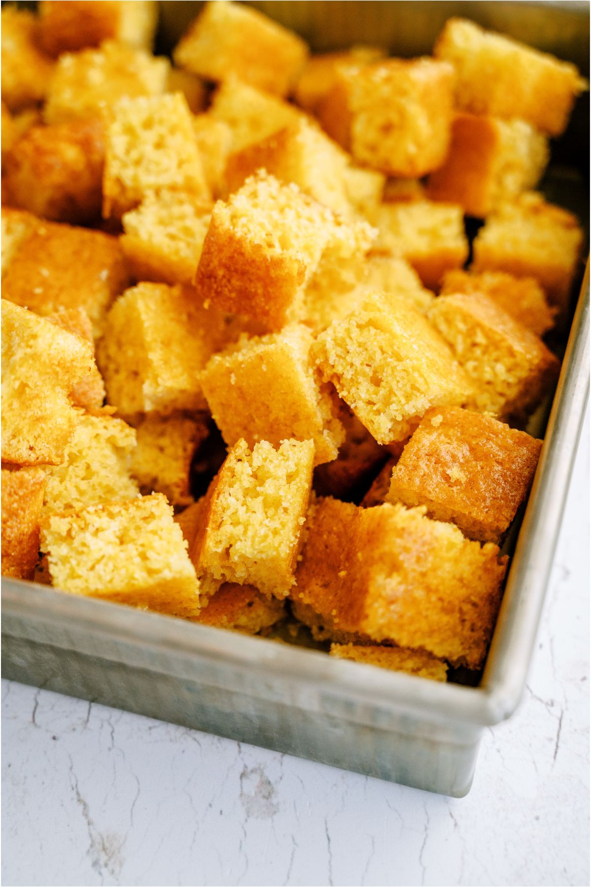 A baking dish full of cornbread cut into cubes.