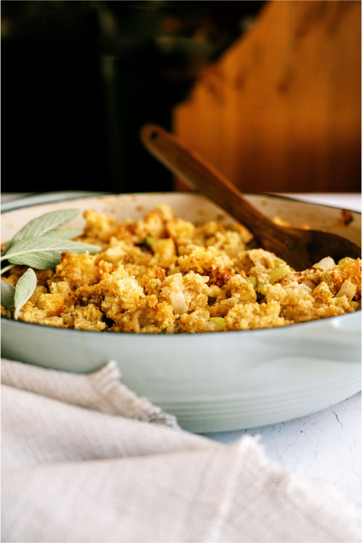 Homemade Cornbread Dressing in a serving bowl with a serving spoon.