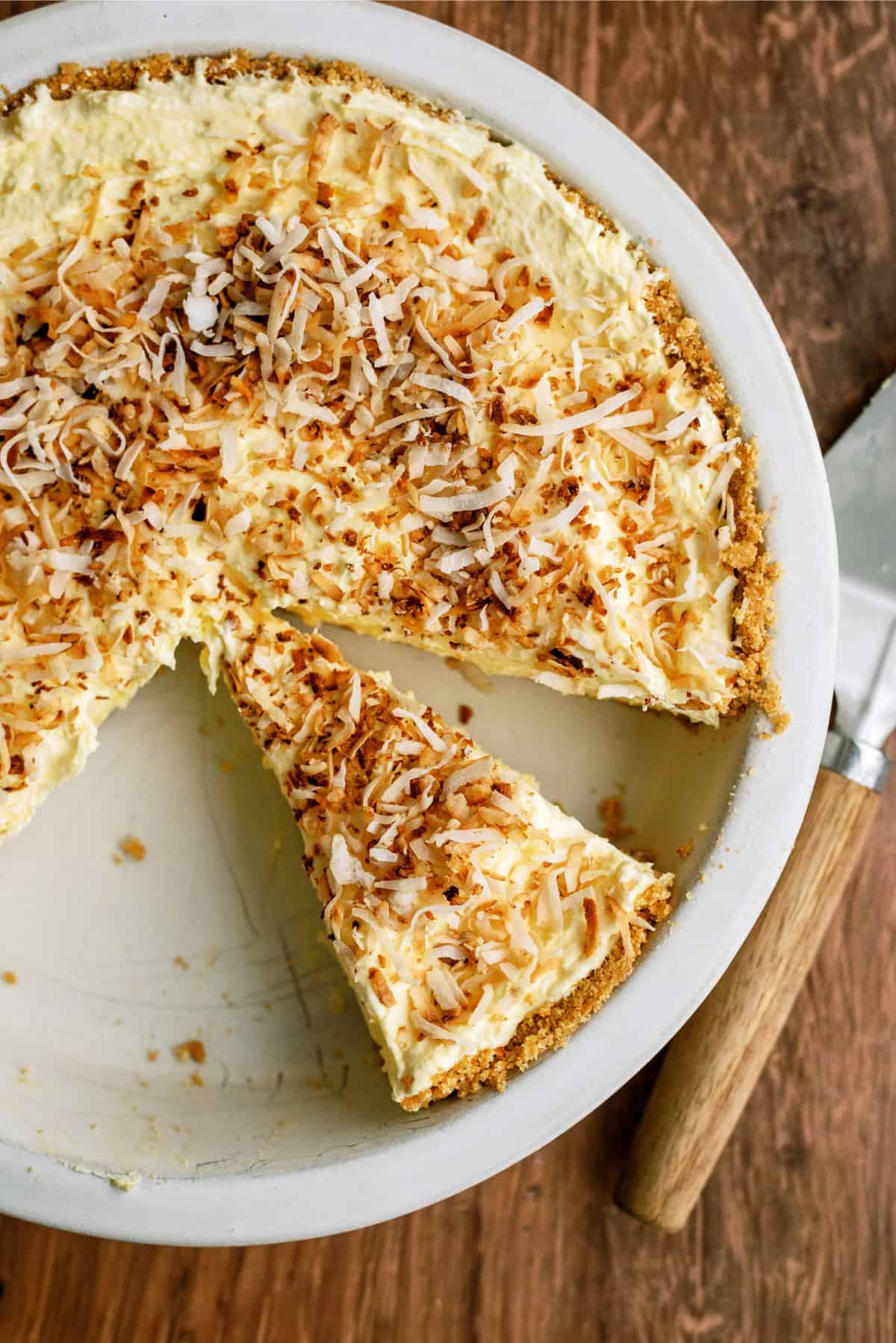 Top view of No Bake Coconut Cream Pie sliced showing one triangle piece separated from the rest all topped with toasted cocnut.