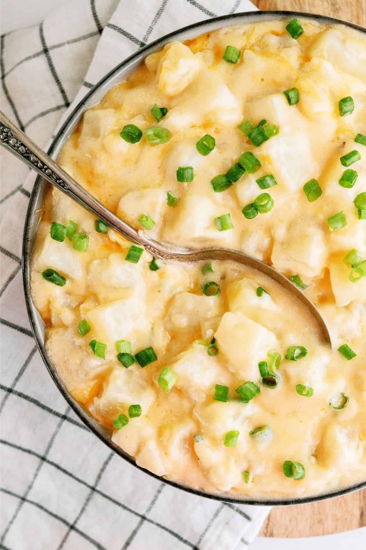 Slow Cooker Cheesy Potatoes in a serving bowl with a spoon