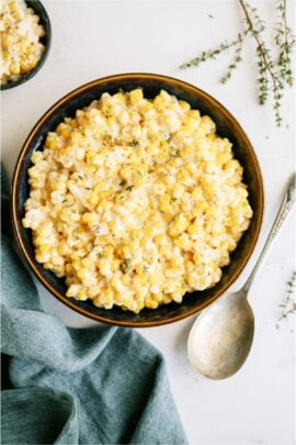 Slow Cooker Creamed Corn in a serving bowl with a serving spoon on the side.