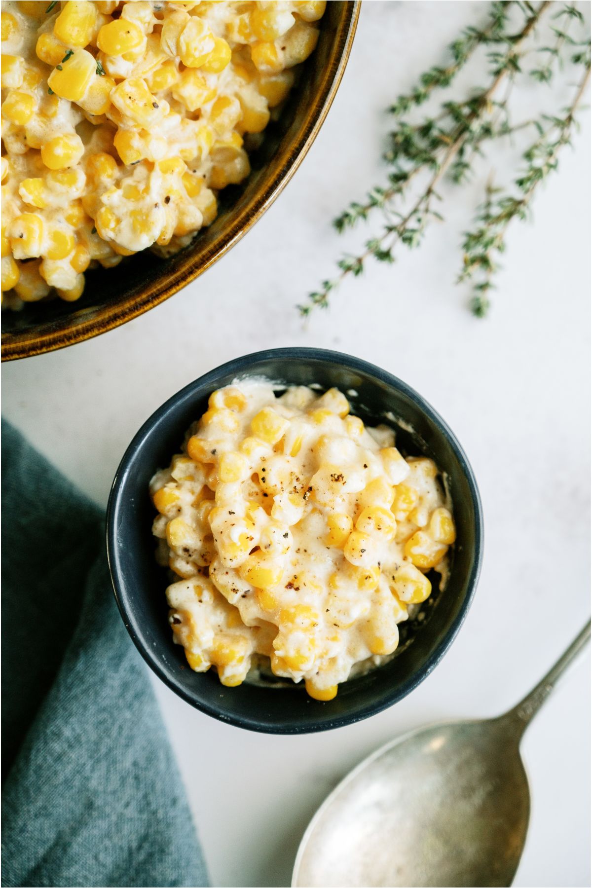 Top view of a small bowl of Slow Cooker Creamed Corn with a larger bowl of Slow Cooker Creamed Corn to the side.