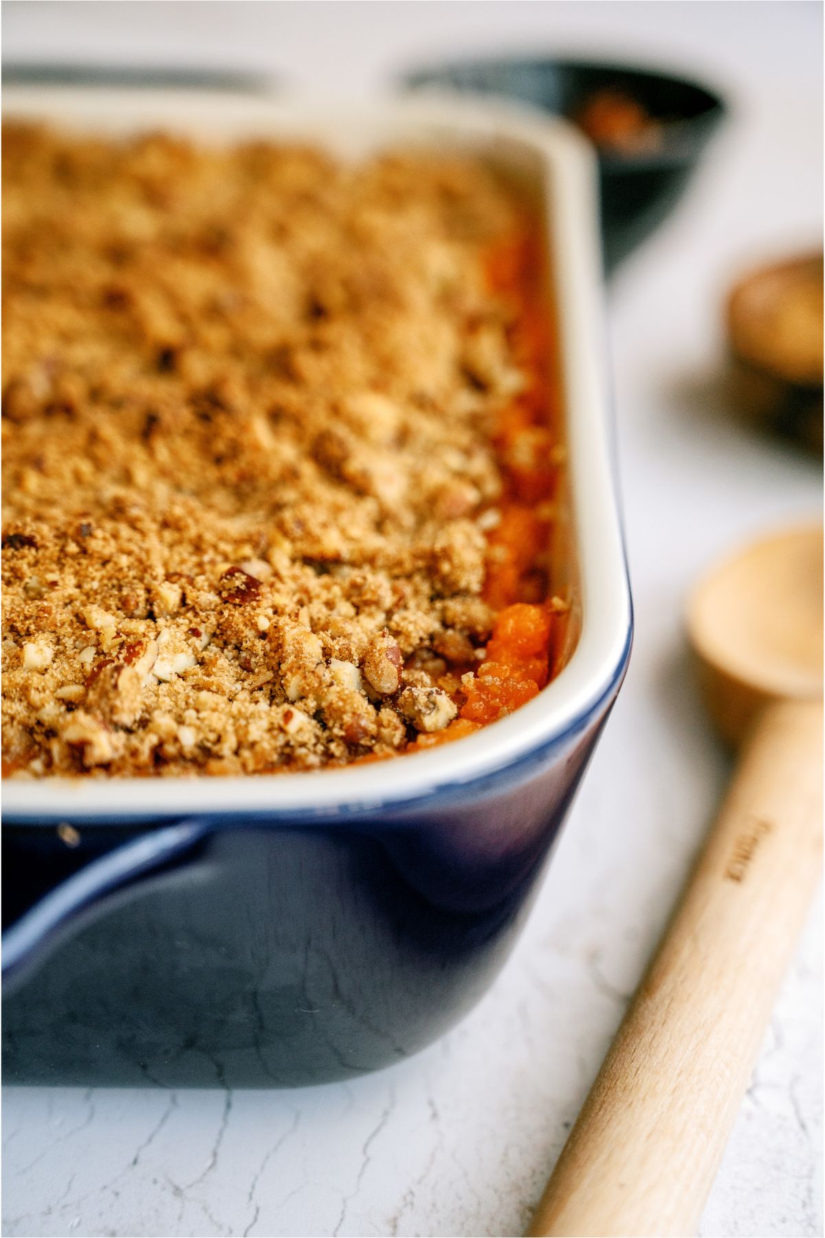 Front view of Sweet Potato Casserole in casserole dish with a wooden spoon on the side of the dish.