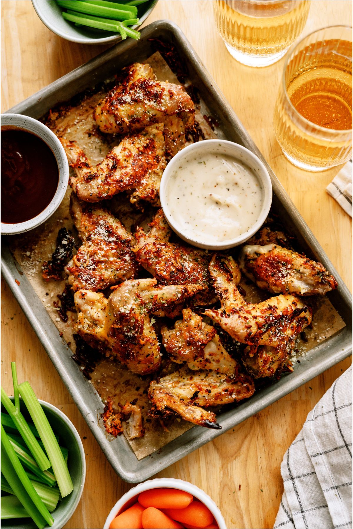 Top view of a pan of Air Fryer Garlic Parmesan Chicken Wings with two cups of dipping sauces on the pan and celery sticks and carrot sticks off to the side.