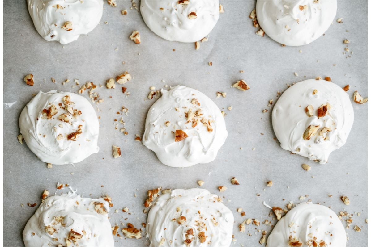 3 rows of divinity lined up on wax paper, topped with chopped pecan pieces.