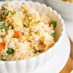 A bowl filled with a serving of Instant Pot Cheesy Chicken and Rice. With an additional bowl and Instant Pot in the background.