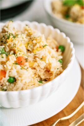 A bowl filled with a serving of Instant Pot Cheesy Chicken and Rice. With an additional bowl and Instant Pot in the background.