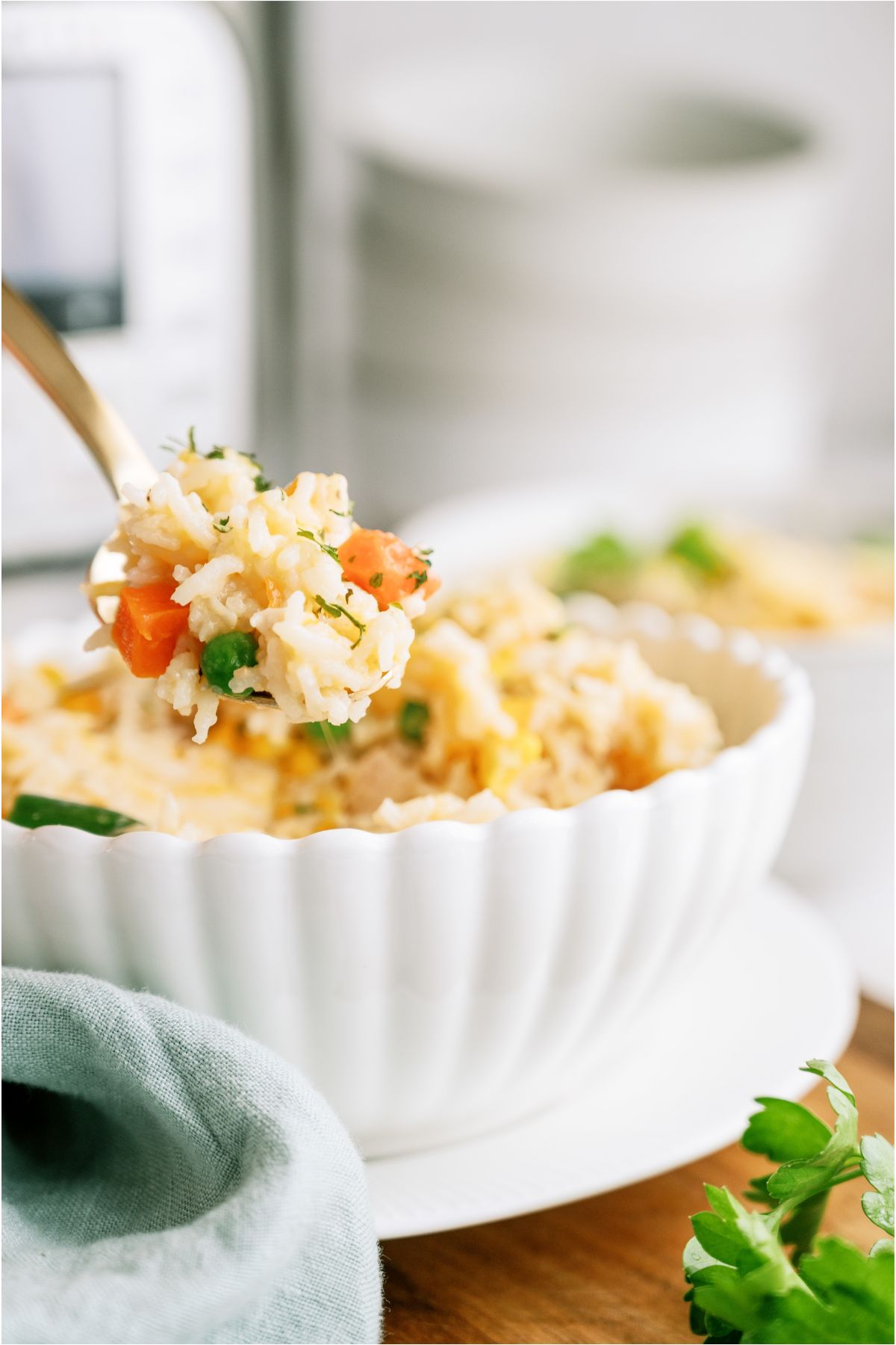 A serving of Instant Pot Cheesy Chicken and Rice in a bowl with a spoon lifting up a bite. An Instant Pot in the background.