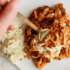 A serving of Million Dollar Casserole (Spaghetti Casserole) on a plate with a fork