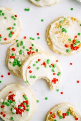 Top view of Super Soft Sugar Cookies frosted and with sprinkles. Two stacked on top of each other with the top one missing a bite.