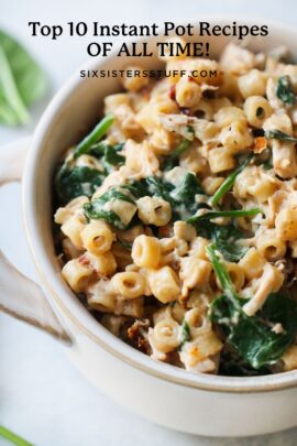 A close-up of a bowl filled with creamy pasta, spinach, and other ingredients.