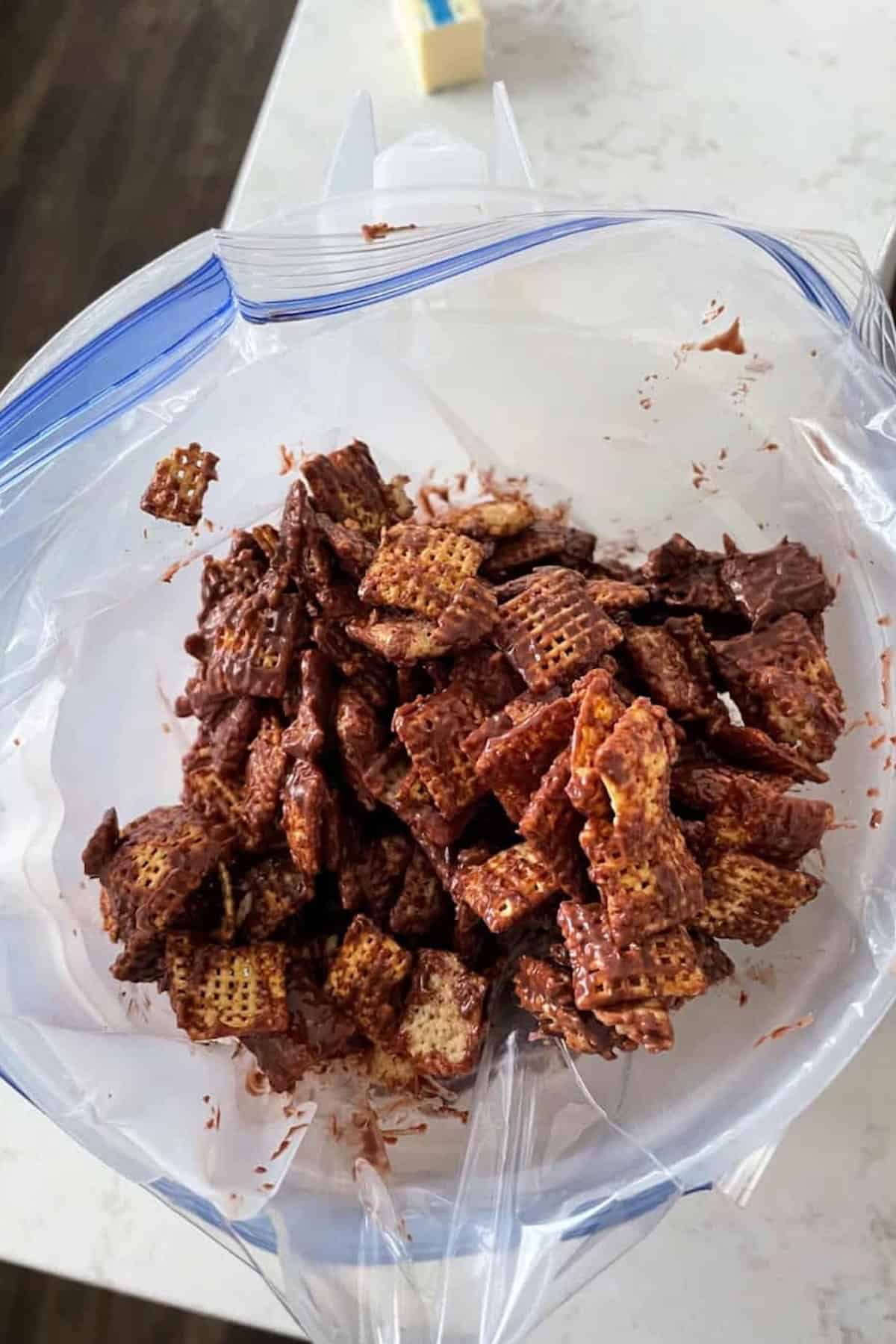 Mix of cereal pieces coated in chocolate inside a resealable plastic bag on a countertop.