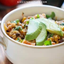 Close-up of a bowl of mixed vegetables and rice topped with sliced avocado.