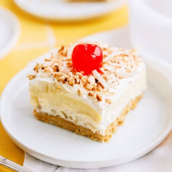 layered pina colada dessert with cherry on a plate