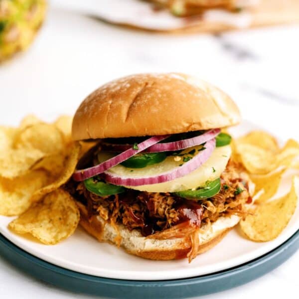 slow cooker pineapple pulled pork sandwiches with chips on a plate
