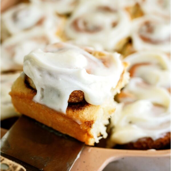 A pan of The BEST Homemade Cinnamon Rolls with a spatula lifting one out