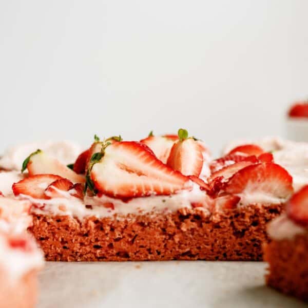 Frosted Strawberry Sheet Cake sliced into pieces