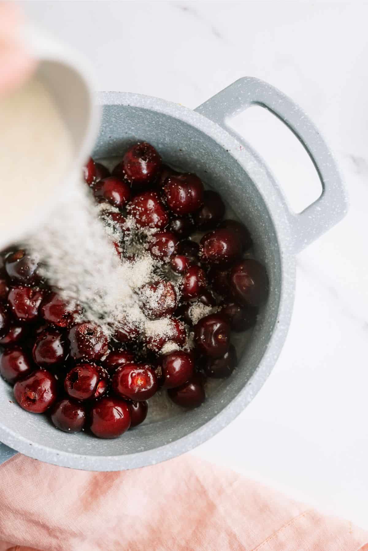 Adding sugar and cornstarch to cherries in a sauce pan