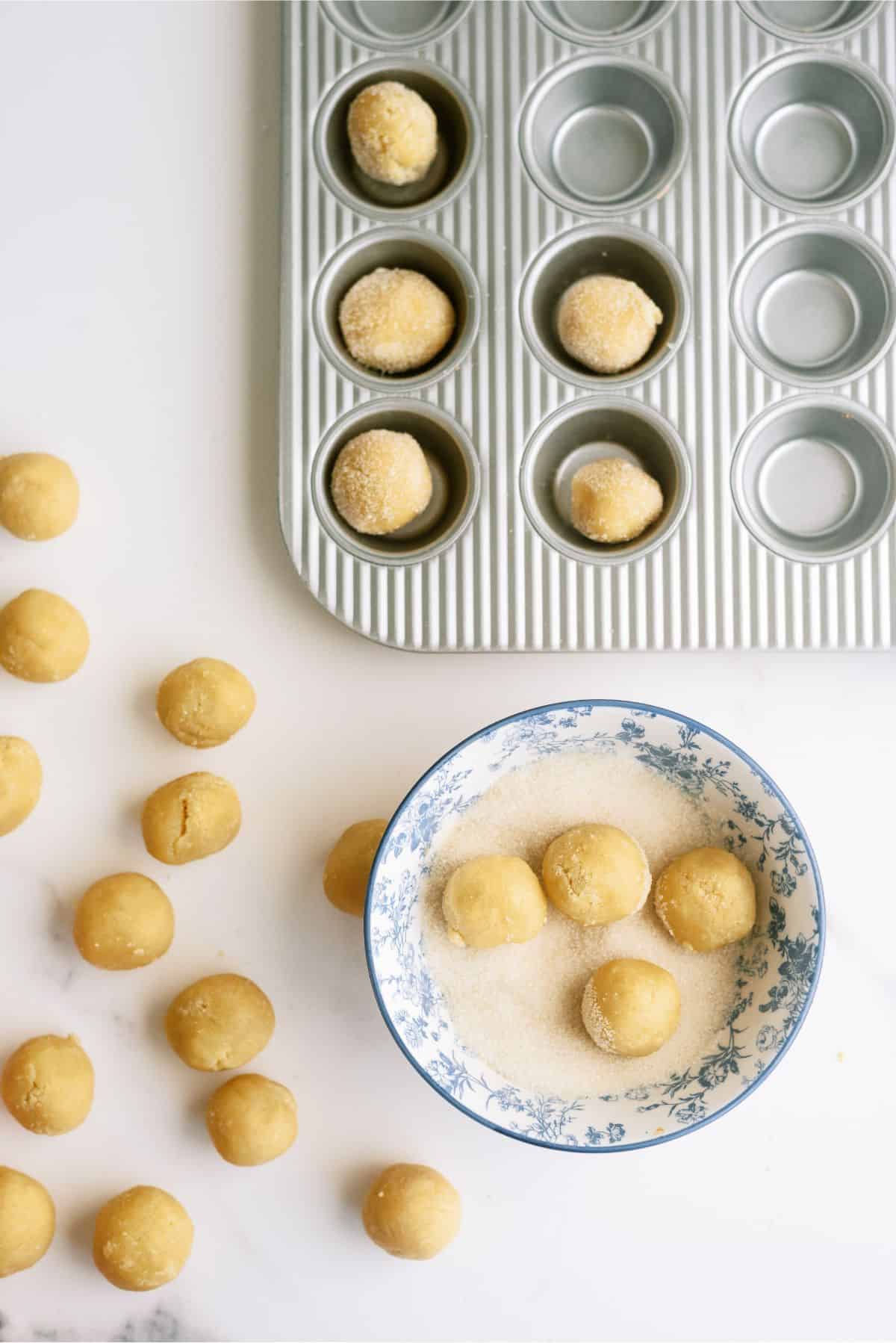 Sugar cookie dough rolled into small balls, dipped in sugar and placed in muffin tin