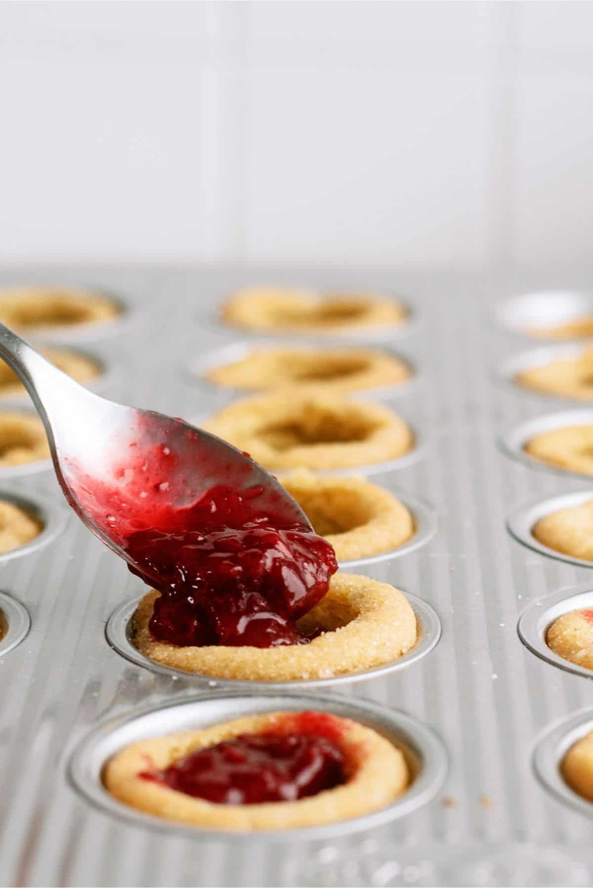 Spooning cherry filling into cookie cups