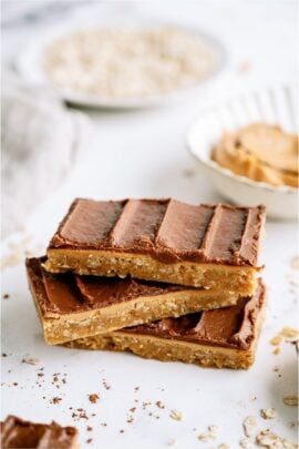 3 chocolate peanut butter bars stacked on top of each other on a white background.