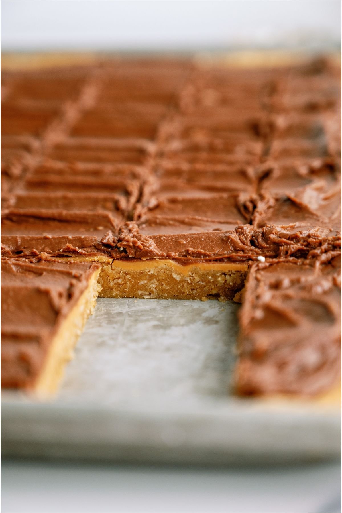 A sheet pan of Lunch Lady Peanut Butter Bars cut into bars. One bar missing to show the inside of the remaining peanut butter bars.