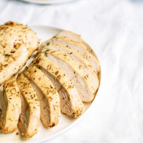 Baked Chicken Breast sliced on a plate with another baked chicken breast.