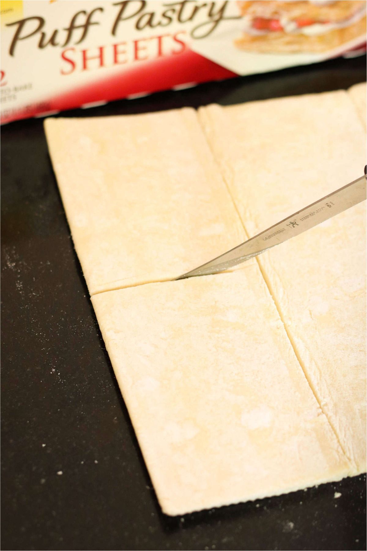 Puff Pastry on the counter top with a knife cutting a section.