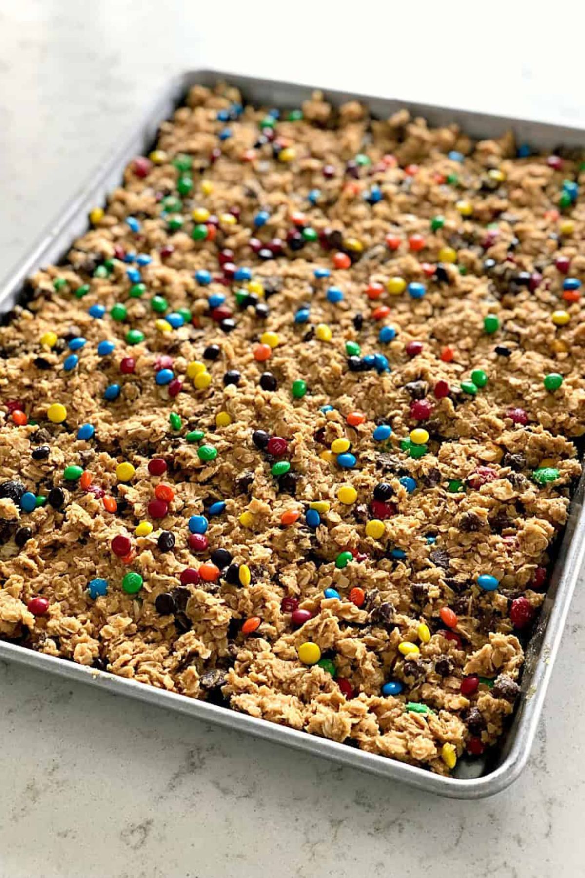 Unbaked M&M Oatmeal Cookie dough pressed in to a large jelly roll pan.