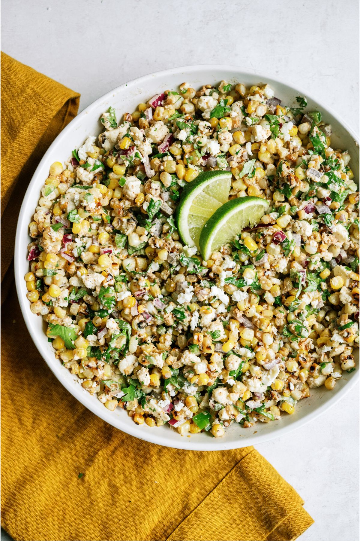 Mexican Street Corn Salad in a large white serving dish topped with two lime slices. 